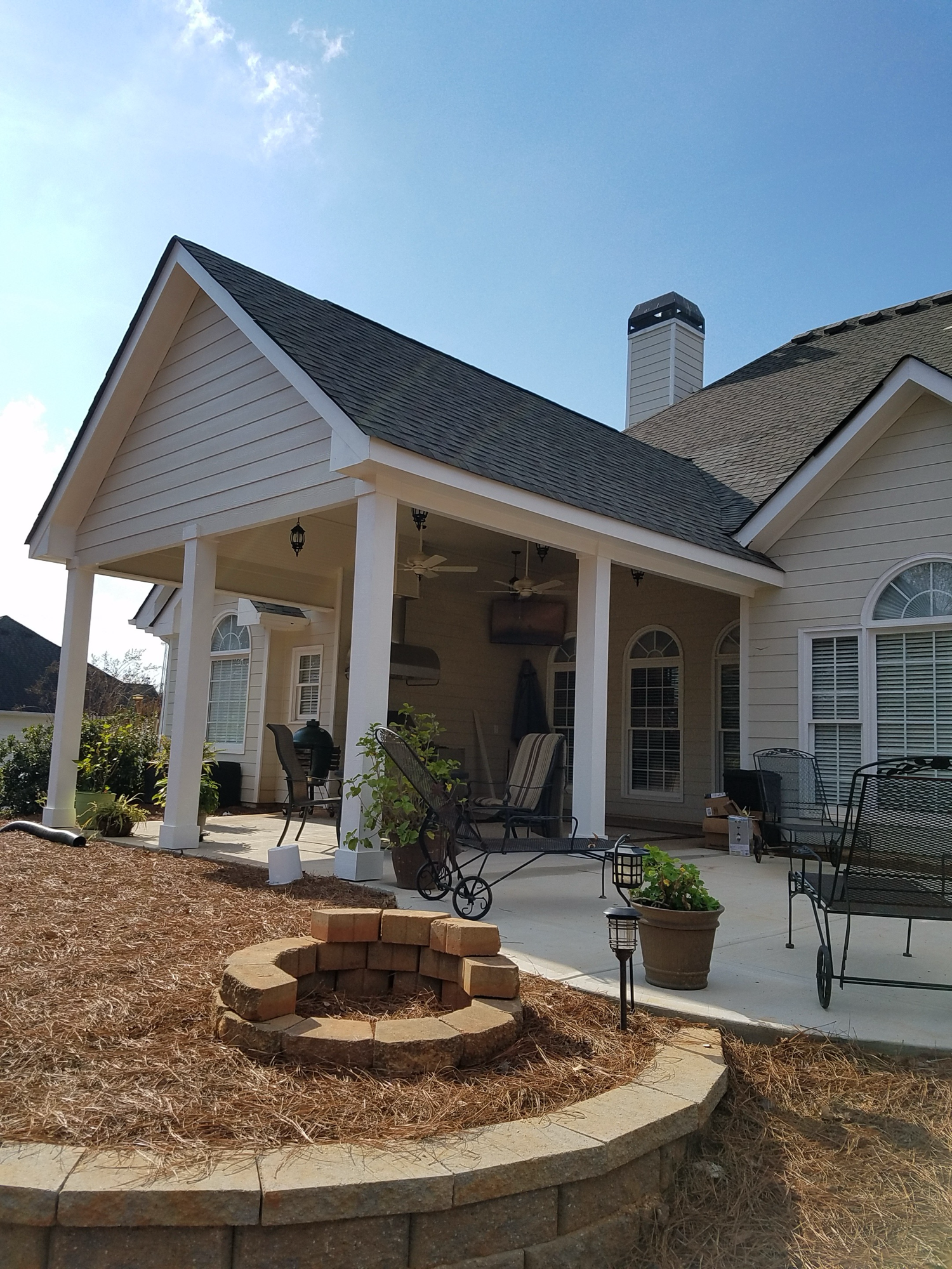 Covered porch addition with stone fire pit and concrete patio — Keystone South Construction